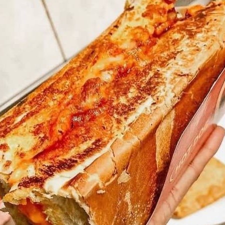 Pão prensado na chapa com casquinha crocante, salsicha ou linguiça, calabresa moída, bacon, cheddar, milho, tomate, cebola dourada na chapa com shoyu, maionese, ketchup e batata palha.