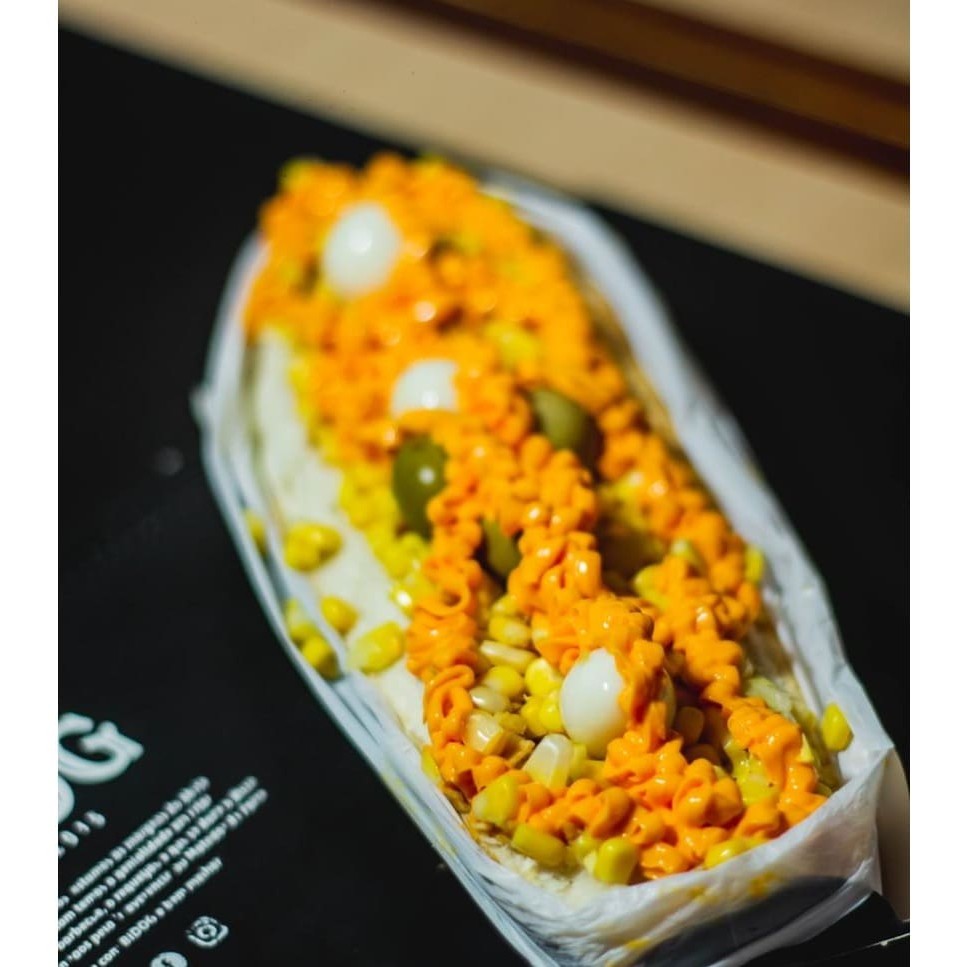 Pão super, salsicha, ketchup, maionese, batata, ovo de codorna, milho e cheddar.