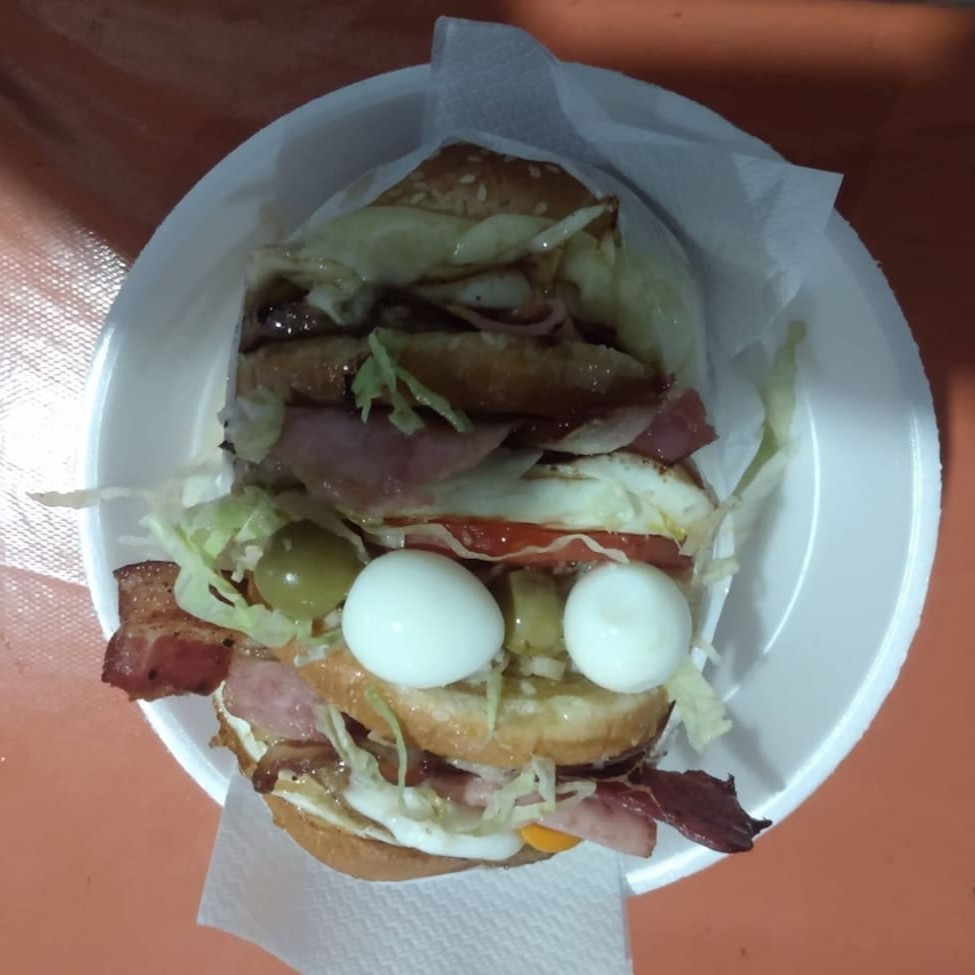 Nosso irresistível Bigtrem com 3 pães fresquinho, 2 suculentas carnes, 2 queijos derretidos, 2 presuntos defumado, 2x bacon crocante e 2x saborosa calabresa. Para uma textura extra, adicionamos batata palha crocante, milho e um delicioso molho cheddar e Catupiry uma porção de alface fresca e tomate suculento. Satisfaça o seu desejo de um Trembão completo e delicioso!