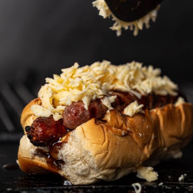 Pão especial, linguiça de costela angus, queijo gratinado, bacon e molho bbq. Fritas Simples Pequena