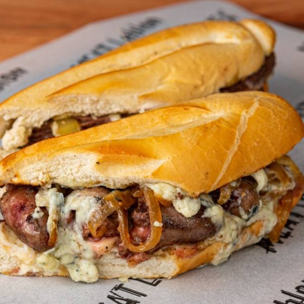 Baguette, coração de frango, Catupiry, queijo gratinado, molho chimichurri e cebola caramelizada.