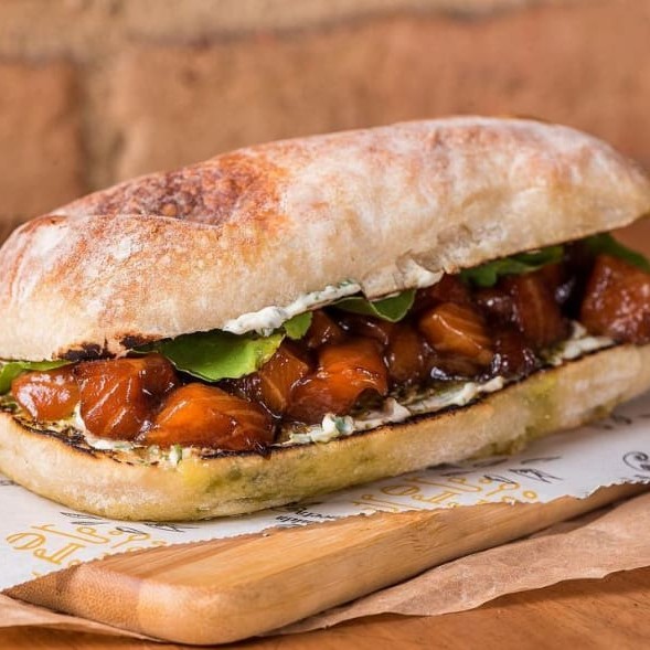 Pão ciabatta, salmão marinado em cubos, cream cheese, rúcula, pesto, coentro e teriaky.