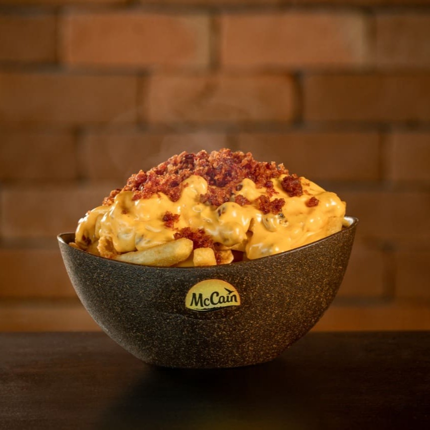 Nossas deliciosas batatas servidas com creme de cheddar e farofa de bacon crocante.