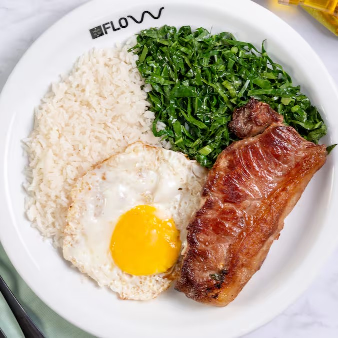 A cara do prato feito perfeito! Contrafilé suculento grelhado no ponto certo, acompanhado de ovo frito com gema molinha (ou no capricho, como preferir!), arroz soltinho e couve refogada no alho que completa o sabor com aquele toque caseiro. Um combo simples, clássico e cheio de sabor!