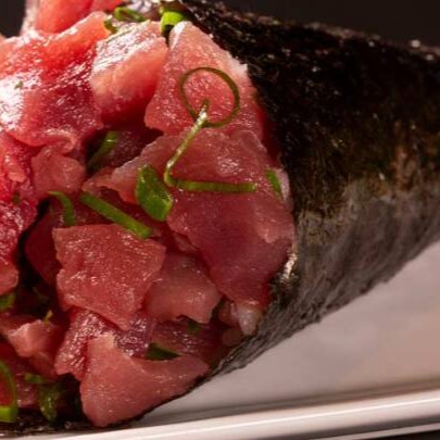 """Temaki de atum preparado com alga crocante, arroz temperado e uma generosa porção de atum fresco, cortado em cubos suculentos para garantir sabor e maciez. Finalizado com cream cheese cremoso que equilibra perfeitamente o frescor do peixe, é enrolado na hora para preservar a textura e a qualidade, proporcionando uma explosão de sabor a cada mordida."""