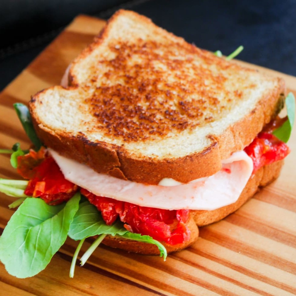 Sanduíche de blanquet, tomate seco, alface e requeijão .