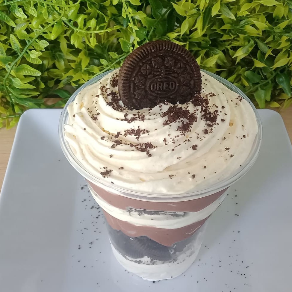 Descubra o encanto do nosso 'Copo da Felicidade Óreo'. Um deleite irresistível que começa com uma camada de mousse de leite Ninho, acrescentando um toque cremoso e suave. Segue com pedaços crocantes de biscoito Óreo, proporcionando uma textura agradável para o paladar. O coração deste prato é um rico recheio de chocolate, que adiciona uma doçura indulgente. Para finalizar, tudo é coberto com mais biscoito Óreo, para um acabamento perfeito. Uma combinação ousada e deliciosa, perfeita para os amantes de sobremesas indulgentes.