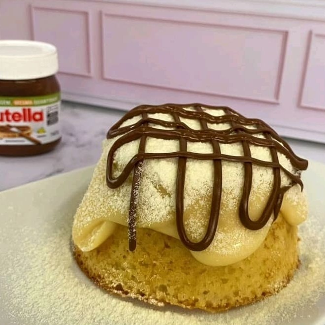 Bolo de massa fofinha e molhadinha de baunilha coberta com recheio bem cremoso de Ninho e Nutella pura, finalizado com leite em pó Ninho polvilhado e fios de Nutella.