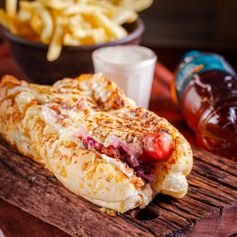 Linguiça artesanal de pernil com alho, Creme de queijos, cebola roxa caramelizada, farofa de bacon, muçarela maçaricada, na baguete de parmesão. + A melhor batata que um delivery já teve, + Molho + Refri.