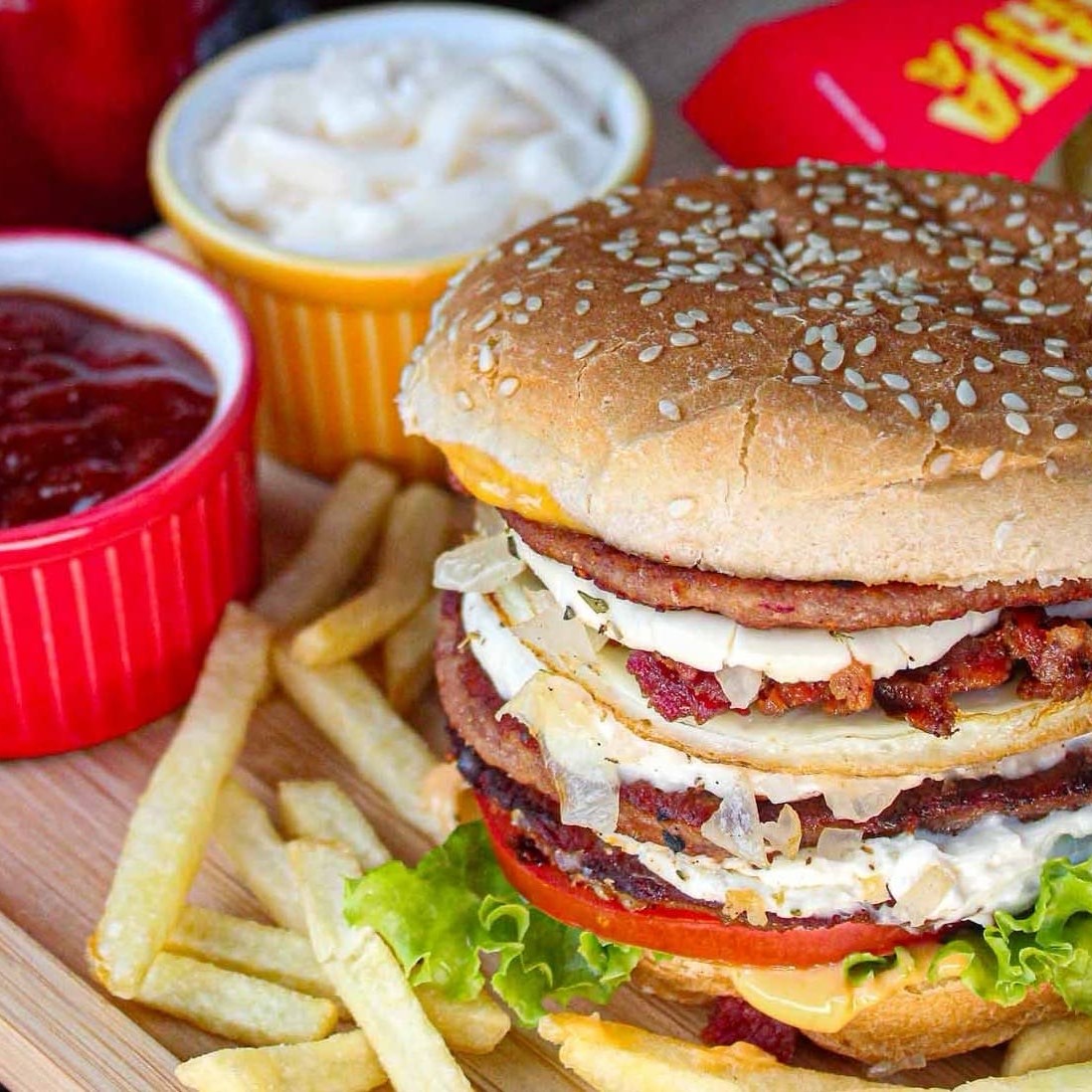 Pão com gergelim, 3 carnes, Catupiry, ovo, bacon, cebola, orégano, alface, tomate e molho. + Coca 350 ml e batata frita