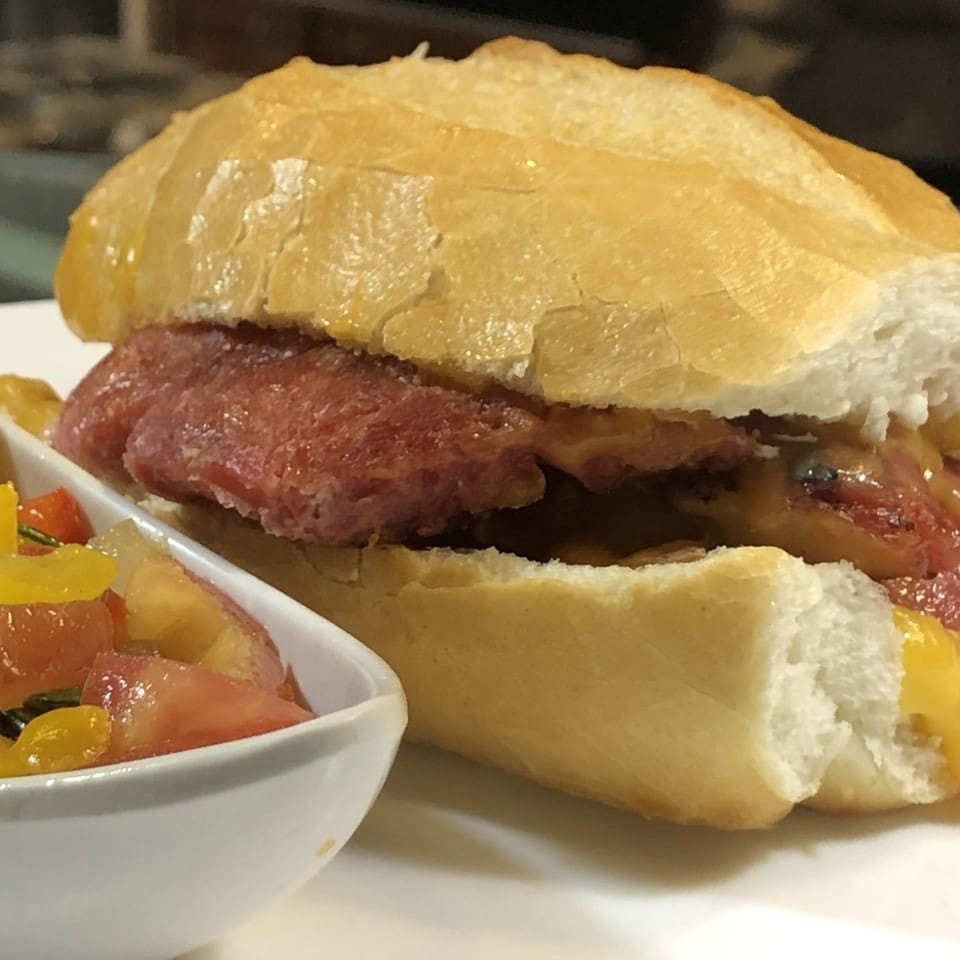 Um delicioso Choripan na versão exclusiva Pão e Companhia. Um sanduiche de linguiça de pernil artesanal no pão francês, patê de alho e queijo prato. Acompanha molho a campanha.