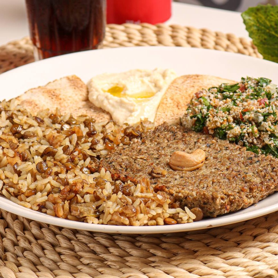 Quibe assado de carne acompanhado de: Tabule Arroz com lentilha Hommus tahine Torradinha temperada