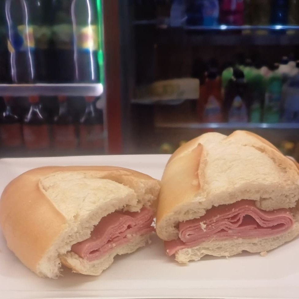 Este é um sanduíche de mortadela defumada, delicadamente acomodada em um pão francês crocante e fresco. A mortadela, com sua textura suave e sabor defumado, harmoniza perfeitamente com a crocância do pão francês, criando uma combinação irresistível. Ideal para um almoço rápido ou um lanche da tarde, este sanduíche é uma viagem saborosa à tradicional culinária de rua, repleta de sabor e simplicidade. Uma verdadeira delícia que merece ser saboreada.
