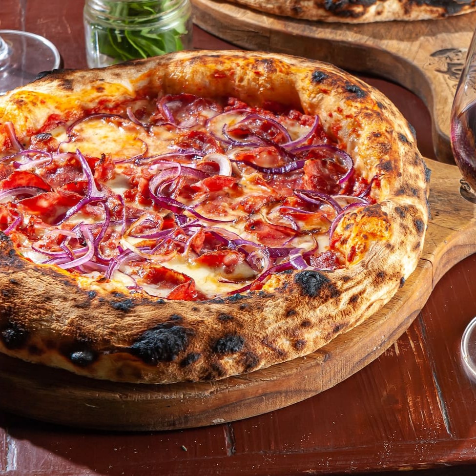 Massa em fermentação natural, molho de tomate, calabresa defumada, mozzarela e cebola roxa