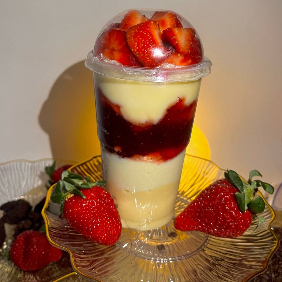 Camadas de creme de Ninho em dose dupla, geleia de morango e morangos cortados na tampa.