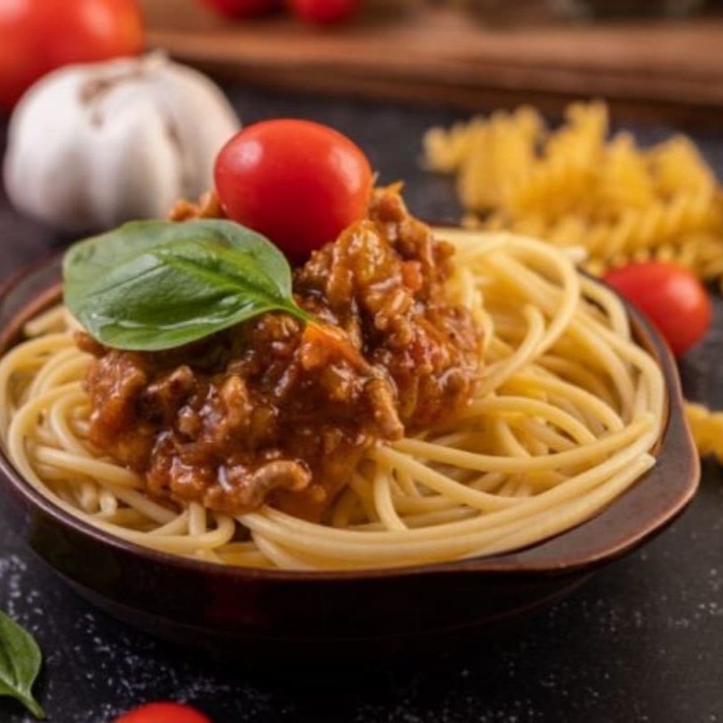 Delicioso espaguete refogado no azeite com saboroso molho a bolonhesa, bacon em cubos, tomates frescos e como toque final uma pitada de orégano