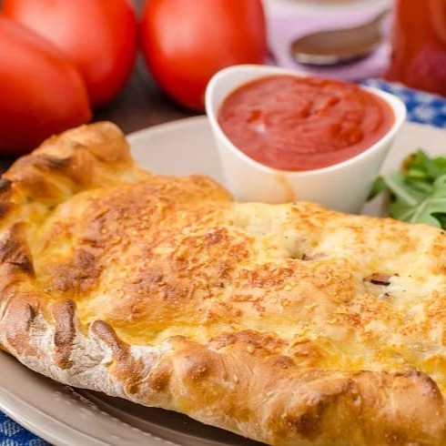 Nosso calzone especial recheado com mussarela de búfala, presunto royale, cebola roxa, tomate cereja, azeitonas pretas, gratinado com parmesão   *Foto ilustrativa
