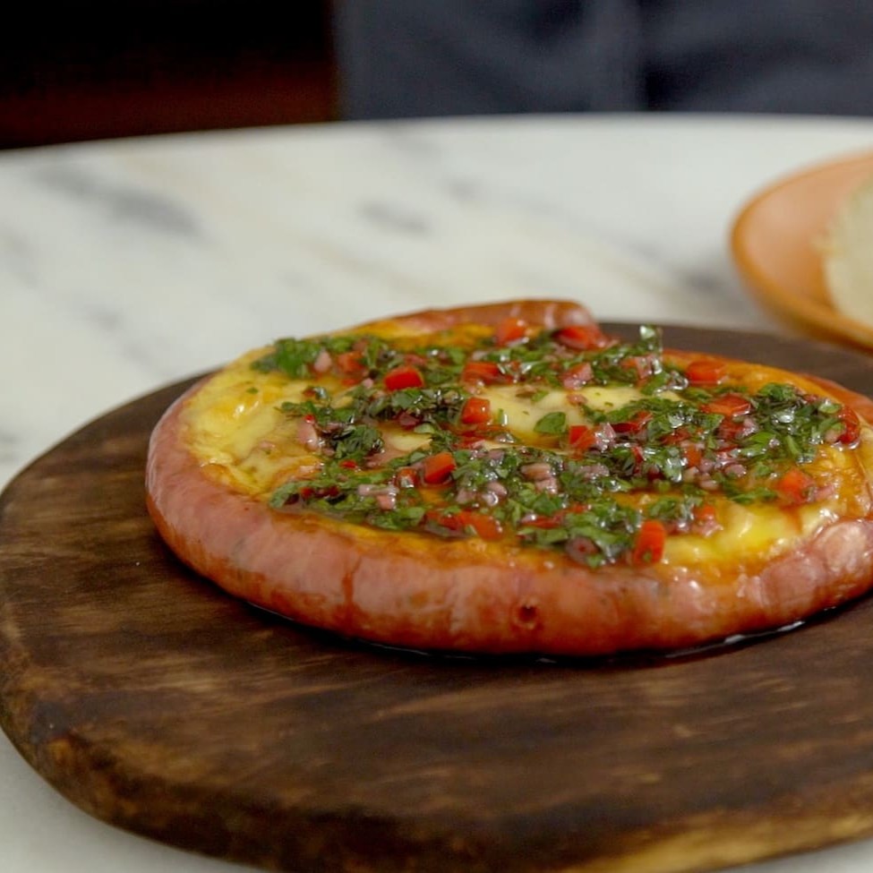 Linguiça mineira temperada e gratinada com queijo acompanhada de mostarda e geleia da casa.