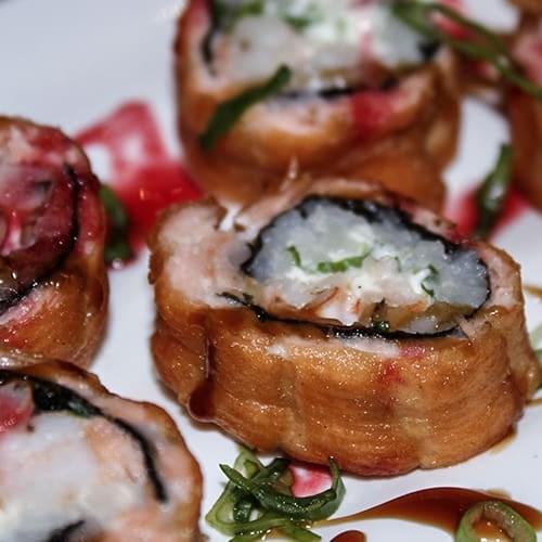 Enrolado de arroz, camarão, cream cheese, mix de cebolinha e alho poró, envolto com salmão e frito.