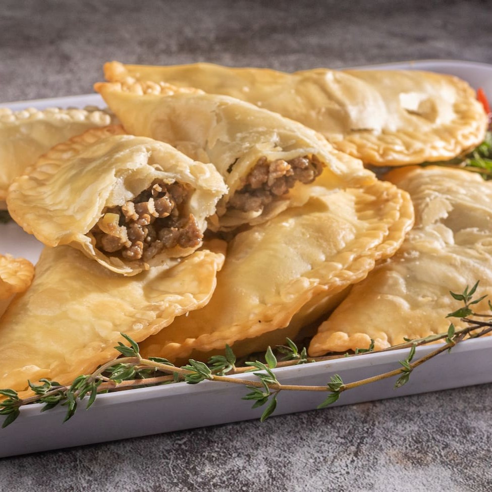 Churrasco da Casa  Uma experiência completa dos sabores do verdadeiro churrasco brasileiro. Este prato reúne um pedaço de frango cuidadosamente temperado e grelhado até alcançar textura macia e suculenta, duas linguiças artesanais com leve toque defumado, e um bife de contrafilé selecionado, preparado na brasa para preservar seu sabor marcante e suculência natural. Acompanhando, dois pães de alho dourados por fora e macios por dentro, além de duas porções de queijo coalho tostadas até o ponto ideal, revelando um contraste perfeito entre o crocante e o cremoso. Finaliza o prato o tradicional molho à campanha, preparado com tomates frescos, cebola roxa, pimentão e um fio de azeite extra virgem, trazendo frescor e equilíbrio ao conjunto.