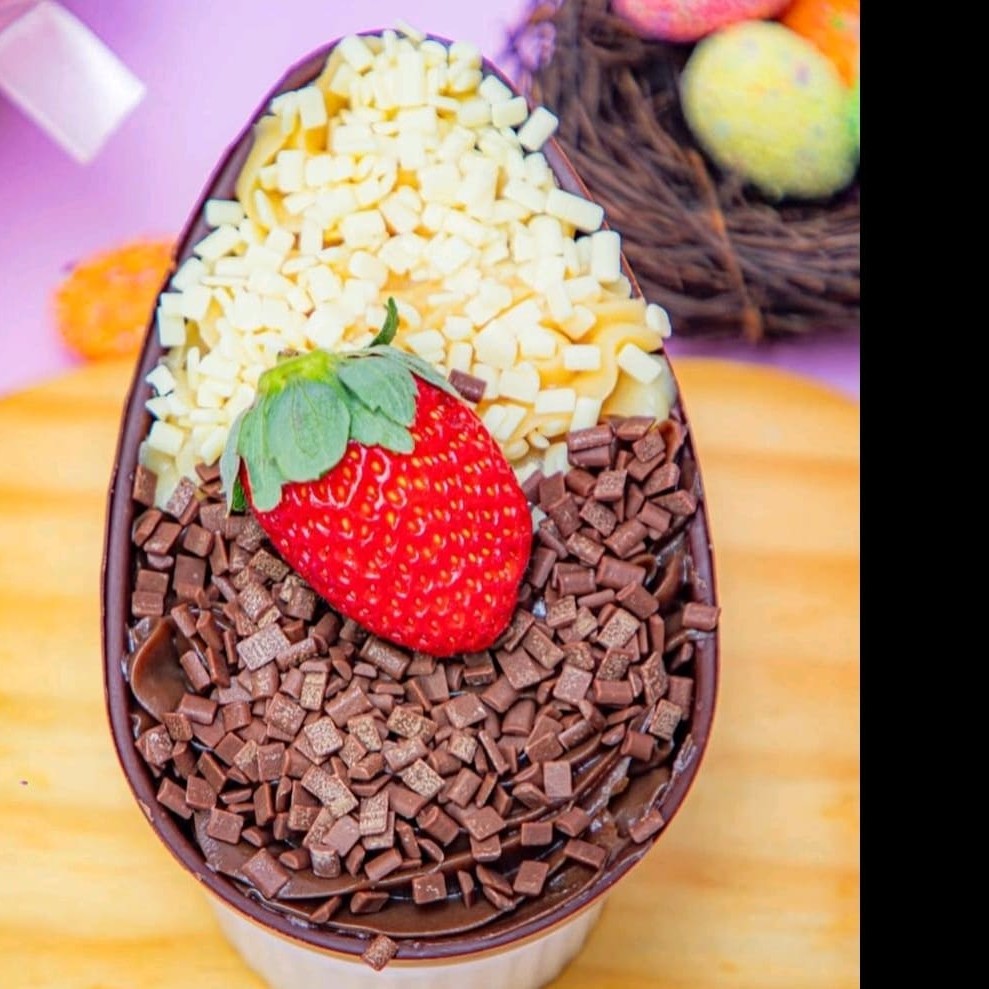 Casca de chocolate com brigadeiro branco e brigadeiro e de enfeite granulado e um morango
