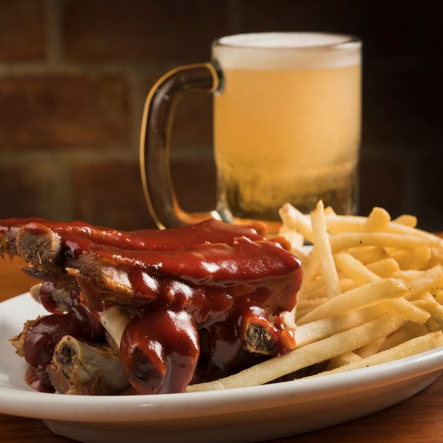 Seis suculentas costelas, regadas ao molho barbecue e servidas com batata frita.