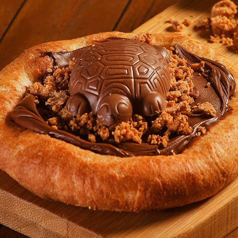 Recheada com o irresístivel sabor do chocolate ao leite, finalizada com paçoca triturada e, no topo, uma tortuguita de chocolate.