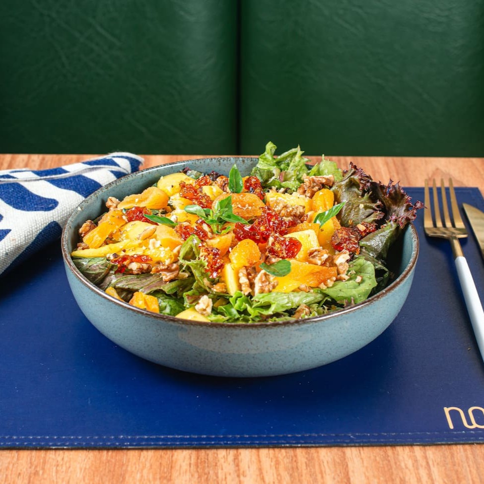 Mix de folhas verdes com pedaços de damasco, manga, nozes picadas, queijo de cabra finalizada com crocantes de amendôas.