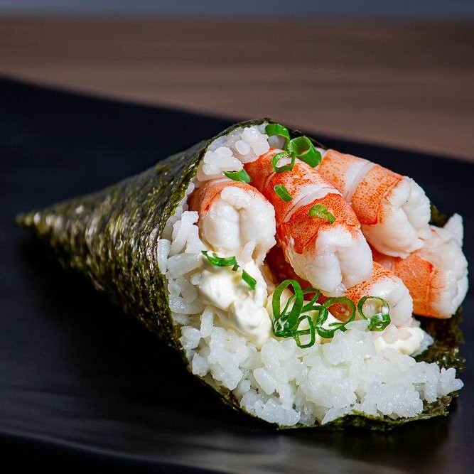 Temaki de camarão, cream cheese e cebolinha

Um temaki feito para surpreender! Essa delícia é preparada com arroz japonês selecionado, envolvido por uma folha crocante de alga nori, recheado com camarões macios e suculentos. O sabor marcante do camarão se equilibra perfeitamente com a cremosidade do cream cheese, criando uma textura irresistível. A cebolinha fresca finaliza com um toque de leveza e aroma, trazendo frescor e harmonia ao conjunto. Ideal para quem busca uma experiência sofisticada, saborosa e cheia de personalidade a cada mordida.
