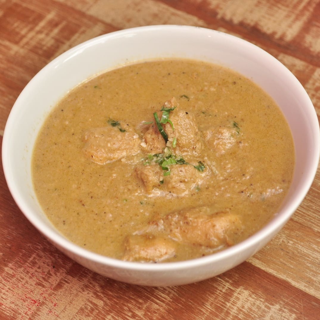 Frango cozido temperado com coco seco, gergelim, especiarias e servido em coco verde.