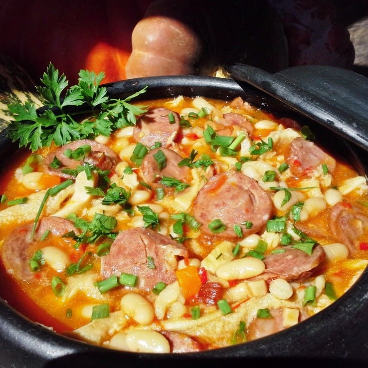 Dobradinha com feijão branco, paio, bacon, azeitonas, batata e cenoura acompanhada de arroz com farofa.