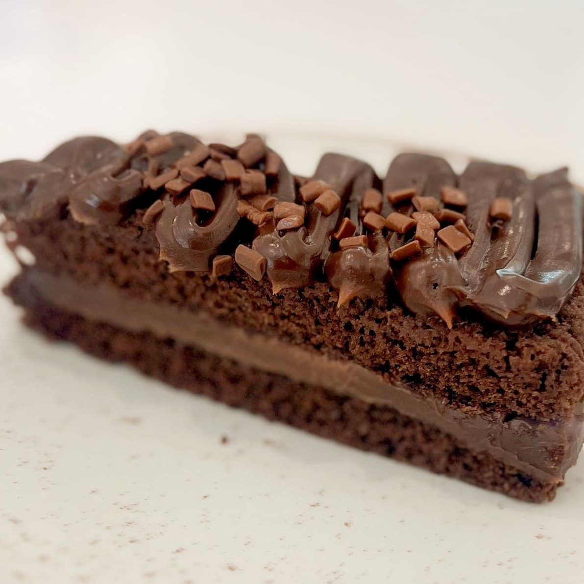 Duas camadas do bolo molhadinho de chocolate recheado com uma camada de brigadeiro cremoso e finalizado com creme de chocolate