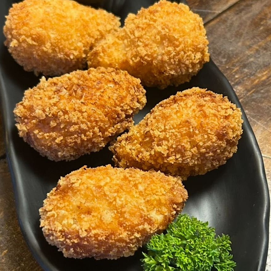 Coxinha sem massa, feito com peito de frango marinado e defumado na casa, catupiry e mozarela, empanado na farinha panko. Acompanha maionese de picles.
