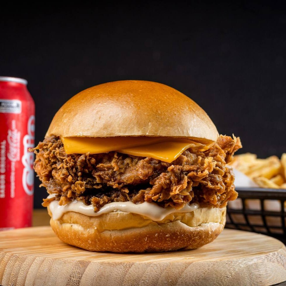 Filé de sobrecoxa crispy (ou 2 filezinhos de peito), queijo cheddar derretido e molho grill, tudo no pão brioche macio. Acompanha batata P crocante e 1 bebida gelada. Sabor marcante, crocância na medida e aquele combo que dá vontade de repetir.