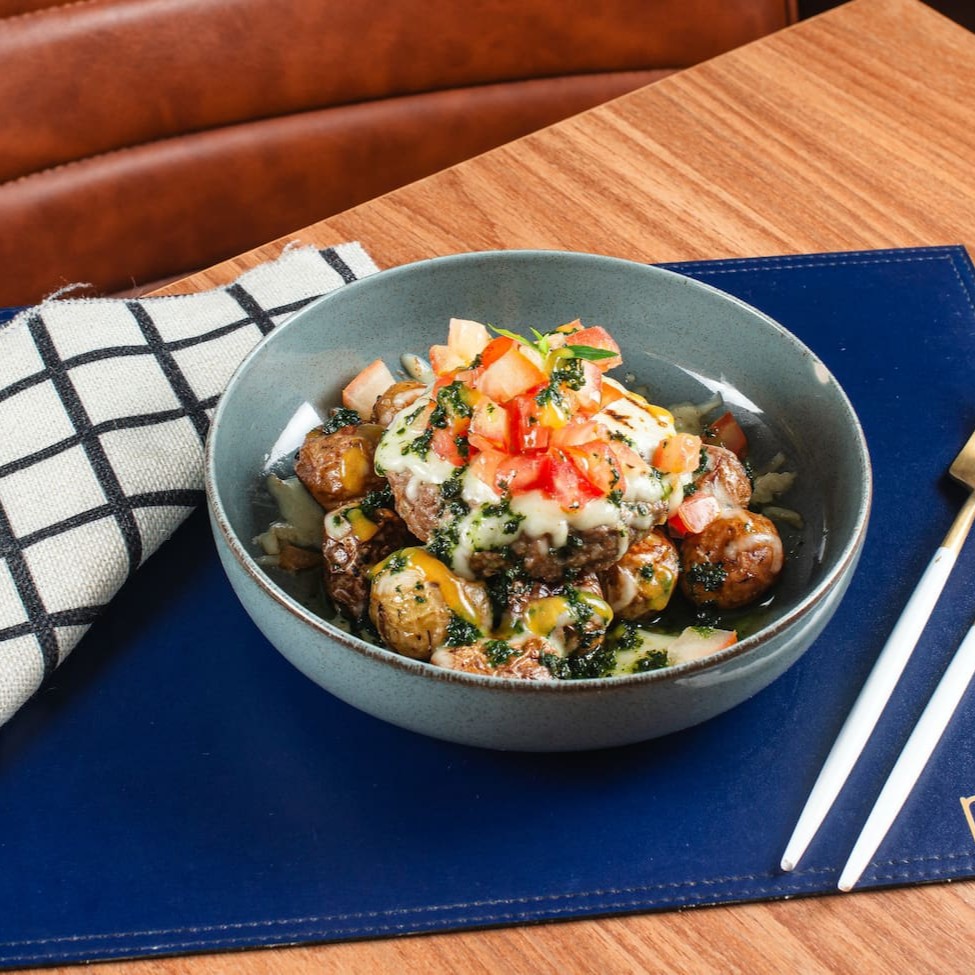 Carne com queijo maçaricado sobre batatinhas calabresas ao forno, vinagrete de tomate, mostarda e pesto.