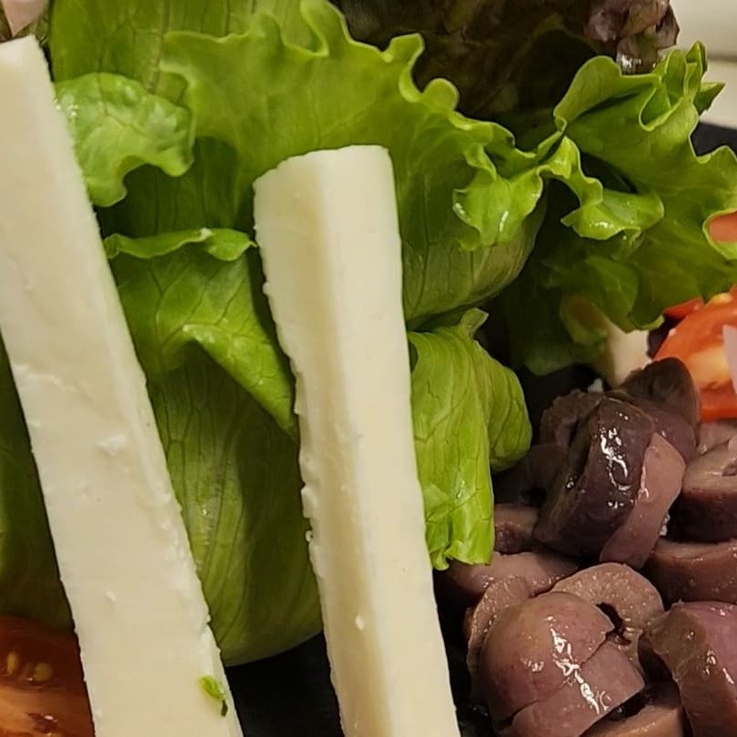 Salada de folhas mistas, queijo parmesão, azeitonas pretas, cebola roxa, tomate cereja, pepino e alcaparras.