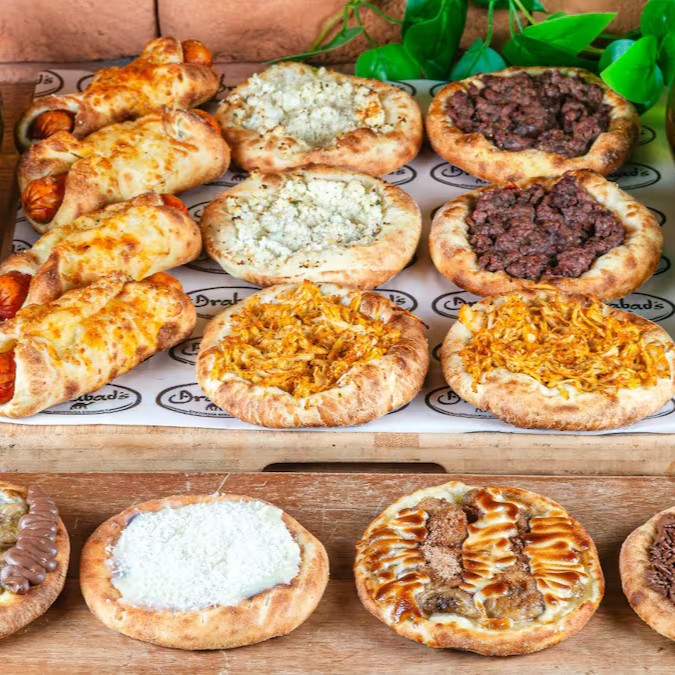 Combo Grupo Feliz: 4 hot dogs, 2 esfihas de carne, 2 de frango, 2 de queijo cremoso, 1 de banana carioca, 1 de banana com chocolate ao leite, 1 de brigadeiro e 1 de beijinho Gourmet. Acompanha 2 Guaranás Antárctica 1,5l.