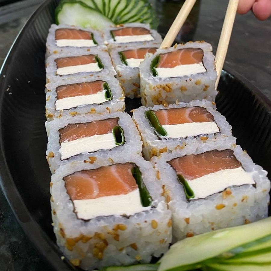 Porção com 10 unidades.  Makimono de salmão, cream cheese, cebolinha, gergelim e arroz (por fora).