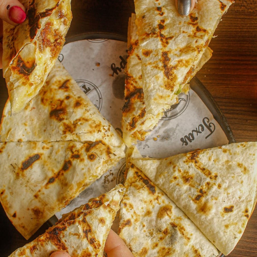 Quesadilla de frango frito, recheada com Crispy chicken, mix de queijos, molho spicy, bacon, Catupiry, e alface.