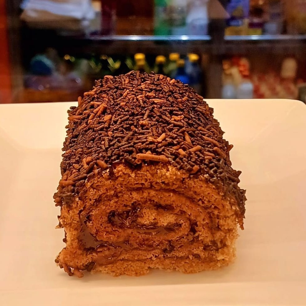 Este rocambole de chocolate é mais do que apenas uma sobremesa. Cada unidade é meticulosamente preparada, apresentando um sabor de chocolate profundo e rico, perfeitamente equilibrado pela doçura. A textura suave e cremosa do recheio se casa perfeitamente com a esponjosidade do bolo, criando uma experiência de degustação verdadeiramente inesquecível. É um prato da nossa categoria Confeitaria Doces que certamente irá encantar os amantes de doces e de chocolate. Uma indulgência que vale cada mordida!