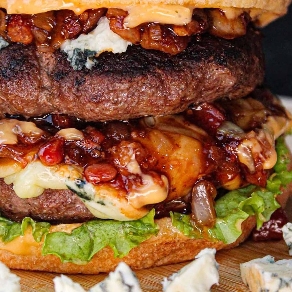 Pão de Brioche, 2 carnes de 130g de Blend da Maju ( total 260 gramas), gorgonzola, muçarela, bastante bacon, cebola caramelizada, alface, tomate e molho.