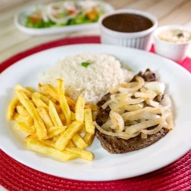 Um prato robusto e saboroso, com bife de contra filé acebolado, preparado com cebola caramelizada. Acompanha arroz soltinho, feijão saboroso, farofa crocante com calabresa (em saquinho separado) e mais um acompanhamento à sua escolha.  Nossas refeições são servidas em embalagem de isopor de aproximadamente 700ml.