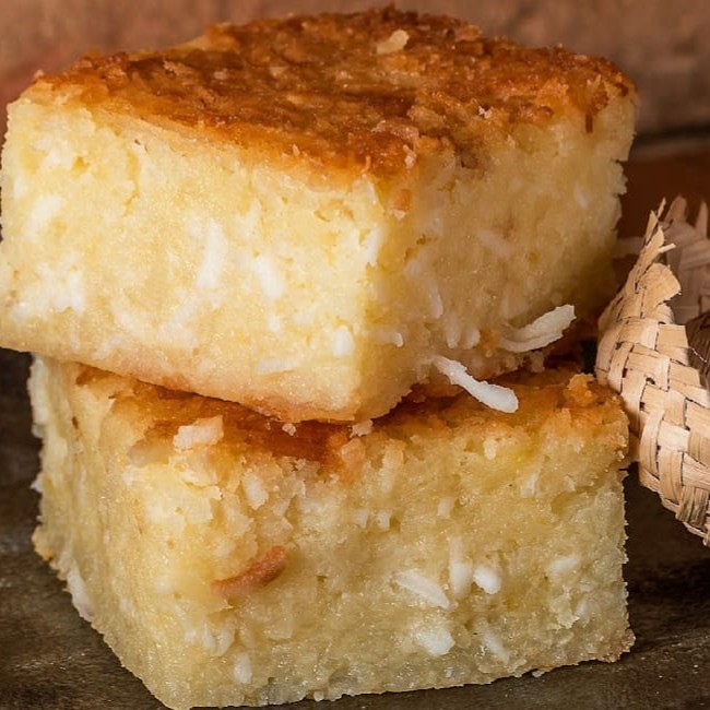 Fatia de bolo de aipim cremoso feito com lascas de coco.  Não contem glúten