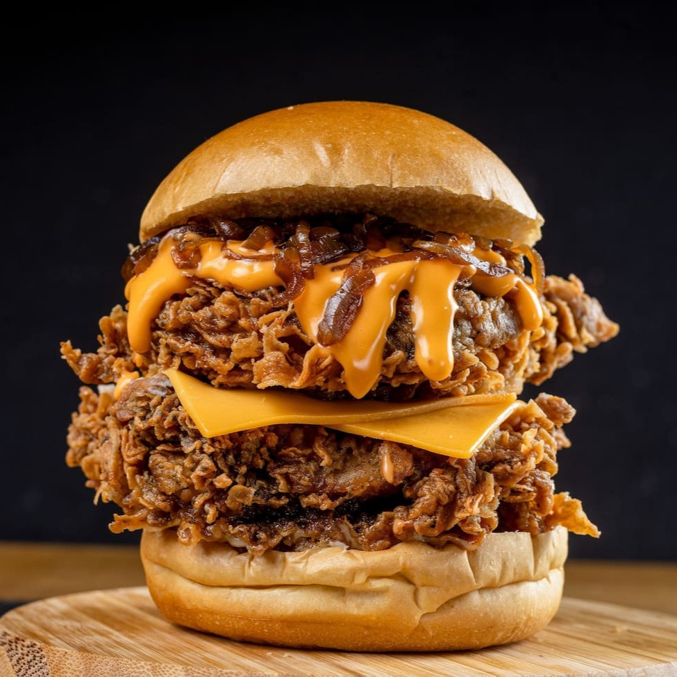 Aqui é pra quem tem fome de verdade! São 2 filés de sobrecoxa (ou 4 filezinhos crispy), queijo cheddar derretido, molho cheddar cremoso e cebola caramelizada, tudo no pão brioche. Grande, suculento e carregado de sabor — sem miséria!