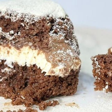 Uma deliciosa fatia de bolo gelado de choconinho, feita com massa de chocolate, recheada com mousse de leite em pó, coberta com brigadeiro gourmet e finalizada com uma generosa camada de leite em pó.