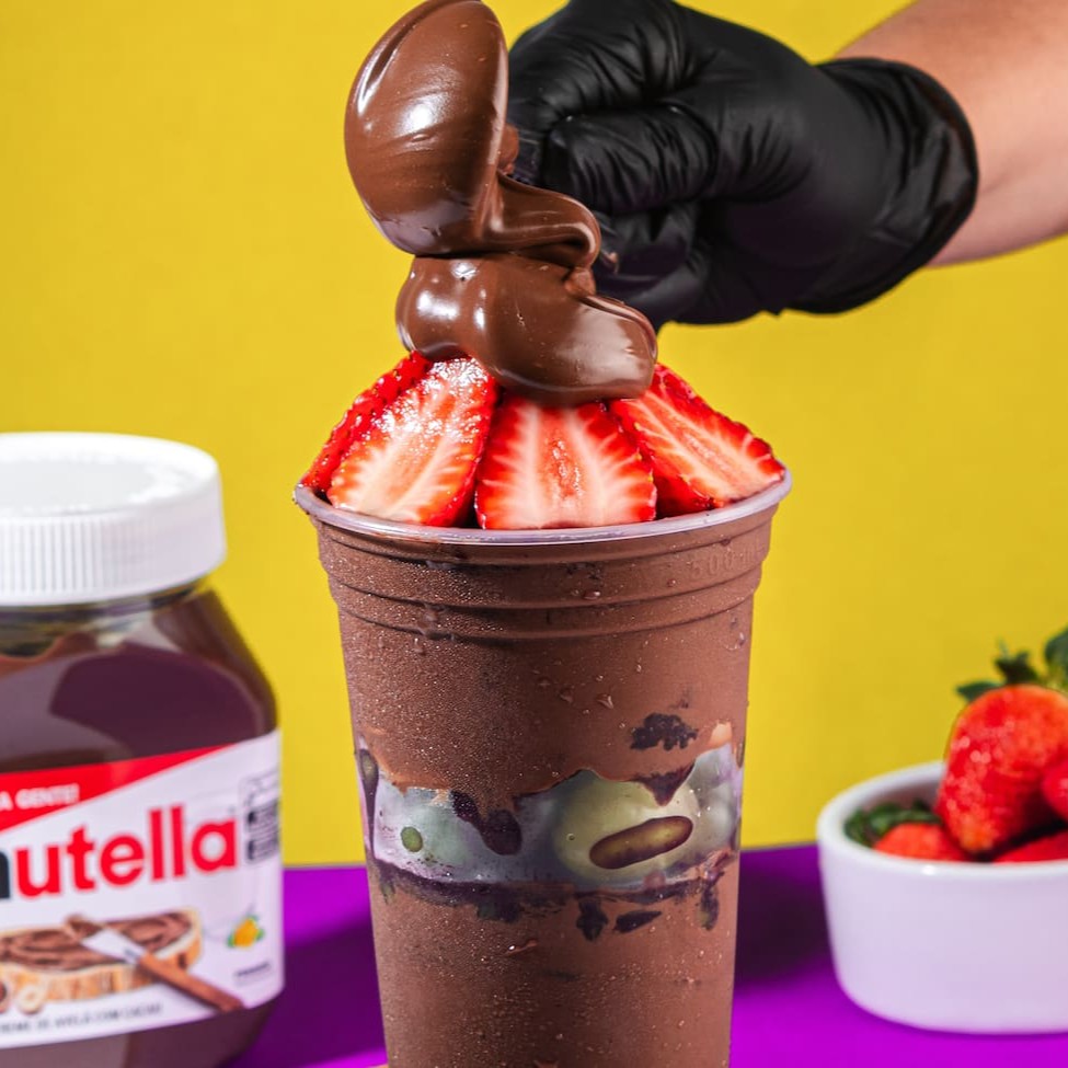 Saboreie nosso autêntico Açaí Tradicional, repleto de pedaços de frutas frescas, generosamente distribuídos no meio do copo e por cima, além disso ainda passamos Nutella no copo e colocamos por cima. Este delicioso manjar é servido em um copo de 700ml, sem economia, garantindo uma experiência gastronômica inigualável. Preparado com uma receita única e inovadora, nosso açaí é cuidadosamente batido com Guaraná, proporcionando um sabor autêntico e surpreendente, que conquista todos os paladares. Além disso, oferecemos uma variedade de complementos gratuitos, para enriquecer ainda mais a sua experiência. Uma combinação saborosa e refrescante, que vai além do convencional. Experimente e surpreenda-se com nosso 'Copo 200ml Nutella', uma inovação na categoria 'Açaí Com Frutas (Pedaços)'!
