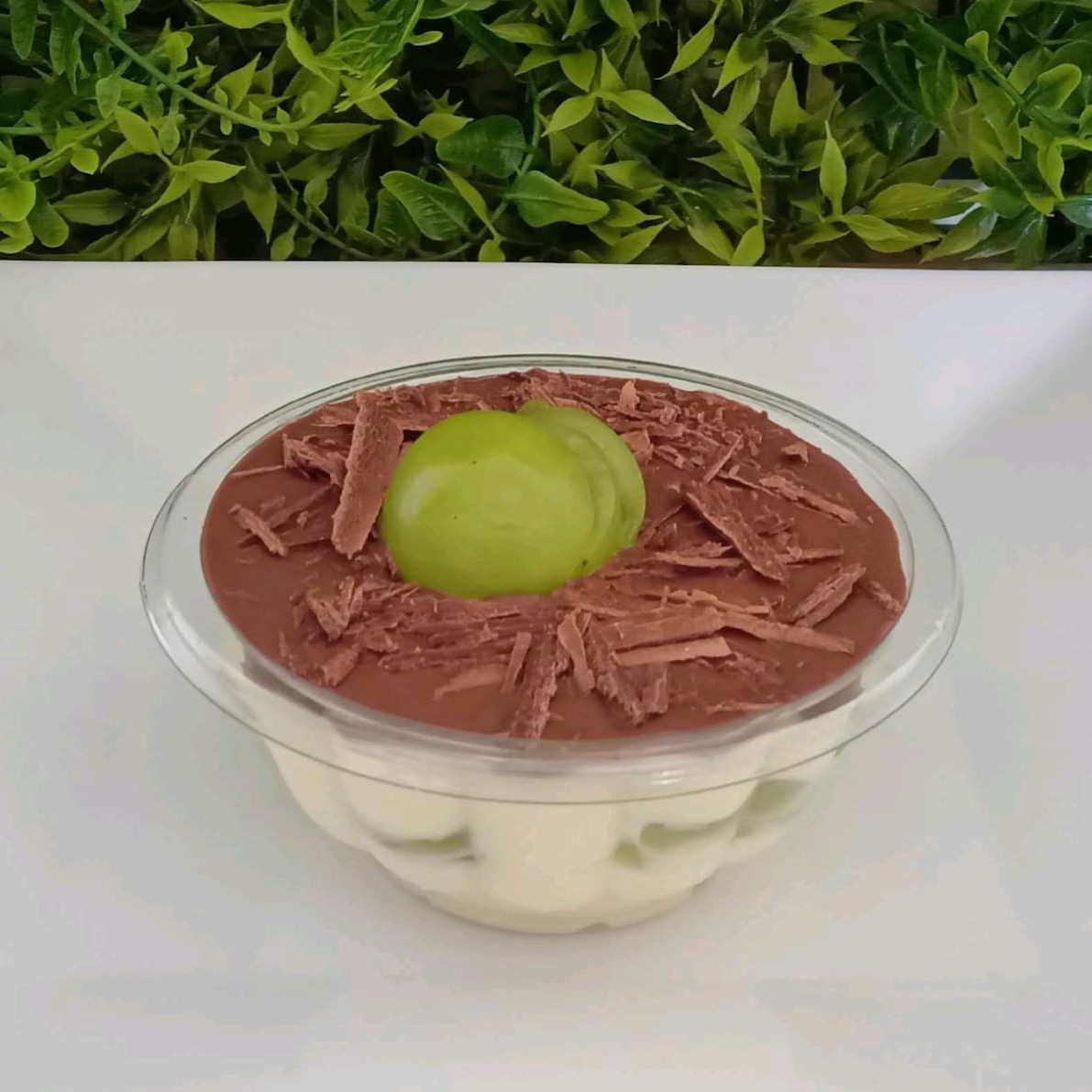 Creme branco de leite Ninho, uvas verde selecionadas e finalizado com ganache e raspas de chocolate.