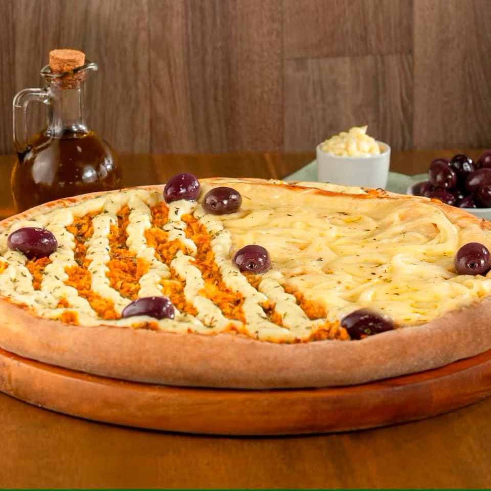 Pizza 1/2 Frango com Catupiry 1/2 Portuguesa (8 fatias): metade com frango desfiado, Catupiry cremoso e mussarela; a outra metade com milho ervilha , palmito ovos, cebola, azeitonas e mussarela.