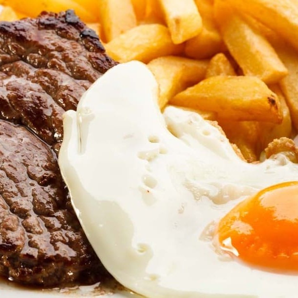Bife cortadinho com um ovo frito por cima, arroz e feijão.