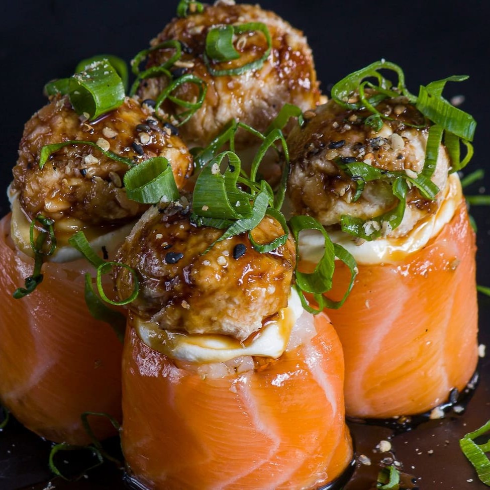 Enrolado de  salmão com cream cheese e arroz, finalizado com pasta de skin e cebolinha.